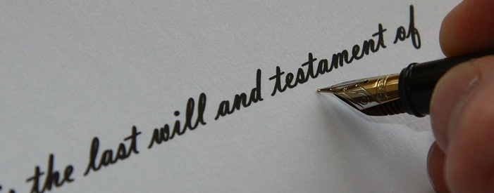hand holding a fountain pen writing the words "the last will and testament of"