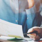 Close up of two people looking at a piece of paper in a business setting.